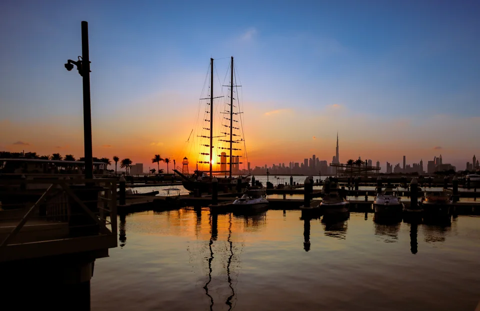Sunset across the creek from Dubai Creek Harbour, with boats and the distant city skyline.